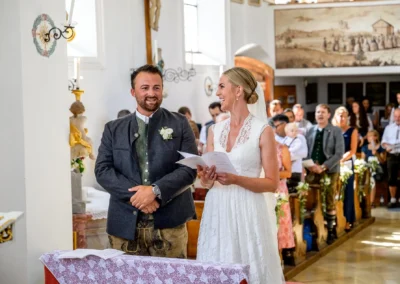 Brautpaar bei kirchlicher Trauung in St. Alban, Diessen am Ammersee, lachend während der Zeremonie in der Kirche.