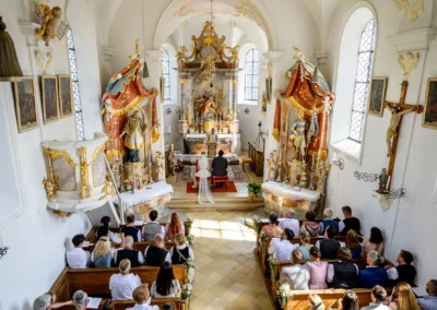 Kirchliche Trauung in St. Alban, Diessen am Ammersee: Brautpaar am Altar umgeben von Gästen in historischer Kirche.