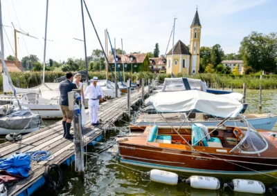 Kirchliche Hochzeit in St. Alban, Diessen am Ammersee, Brautpaar am Steg mit Blick auf die Kirche und Boote.