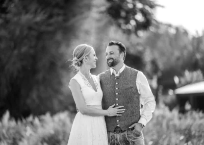 Ein glückliches Brautpaar im Freien, lächelnd und Händchen haltend. Hochzeitsfotograf, romantische Hochzeitsreportage.