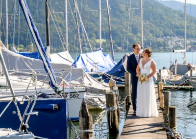 Brautpaar-Shooting am Tegernsee: Romantisches Foto des Paares auf einem Steg in Bad Wiessee an einem sonnigen Tag.