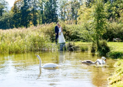 Brautpaar beim Fotoshooting am idyllischen Tegernsee in Bad Wiessee, umgeben von Natur und Schwänen.