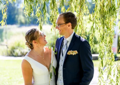 Brautpaar-Shooting am Tegernsee: Glückliches Paar in Bad Wiessee unter Bäumen, romantische Hochzeitsfotografie.