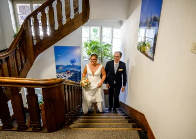 Brautpaar bei standesamtlicher Trauung im Rathaus Bad Wiessee, steigt lächelnd die Treppe hinauf, Hochzeitsreportage.