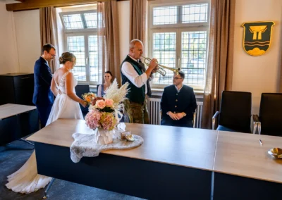 Standesamtliche Trauung im Rathaus Bad Wiessee mit Brautpaar und Trompetenspieler in traditioneller Kleidung.
