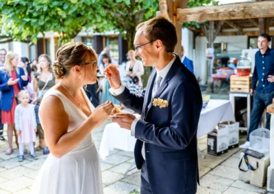 Brautpaar genießt Hochzeitstorte im Bootshaus Terrassenhof Bad Wiessee, umgeben von Gästen.