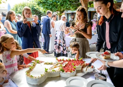 Hochzeitsfeier im Terrassenhof Bad Wiessee: Gäste servieren Torte, festliche Abendveranstaltung im Bootshaus.