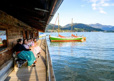 Hochzeitsfeier im Bootshaus Terrassenhof Bad Wiessee, Gäste in traditionellen Outfits am Tegernsee.