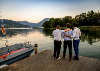 Hochzeitsgäste am Tegernsee bei Sonnenuntergang während einer Feier im Bootshaus, Terrassenhof Bad Wiessee.