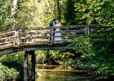 Brautpaar auf Brücke bei Pfaffing, Ebersberg, inmitten idyllischer Waldkulisse während eines Fotoshootings.