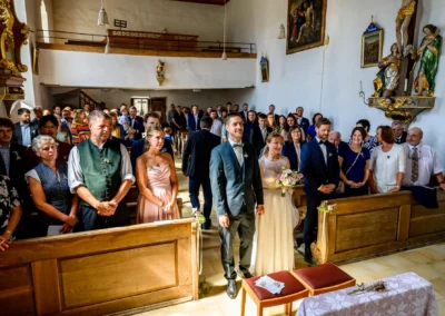 Kirchliche Trauung in St. Margaretha, Pfaffing: Brautpaar vor Altar, umgeben von Gästen. Hochzeitsfotografie Ebersberg.