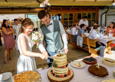 Brautpaar schneidet Hochzeitstorte auf der Feier im Landgut Kugler-Alm, Ebersberg bei München an.