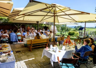Hochzeitsfeier im Freien auf dem Landgut Kugler-Alm in Ebersberg, mit Gästen an gedeckten Tischen.